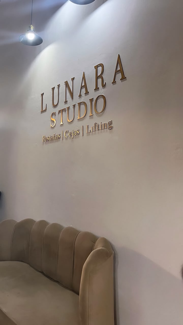 Logo dorado de Lunara Studio sobre la pared del estudio con sofá de terciopelo